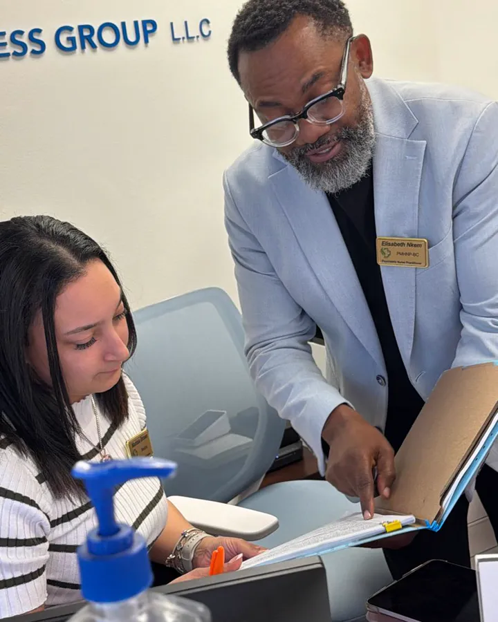 Two adults review a binder together at a desk